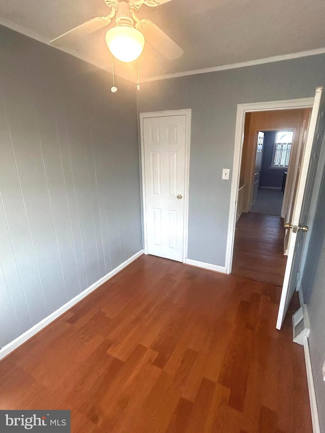 unfurnished bedroom with ceiling fan, dark hardwood / wood-style floors, and crown molding