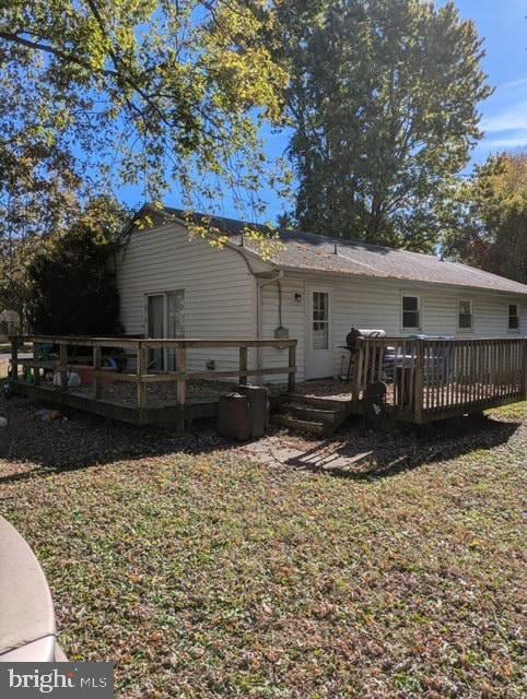 rear view of property featuring a lawn and a deck