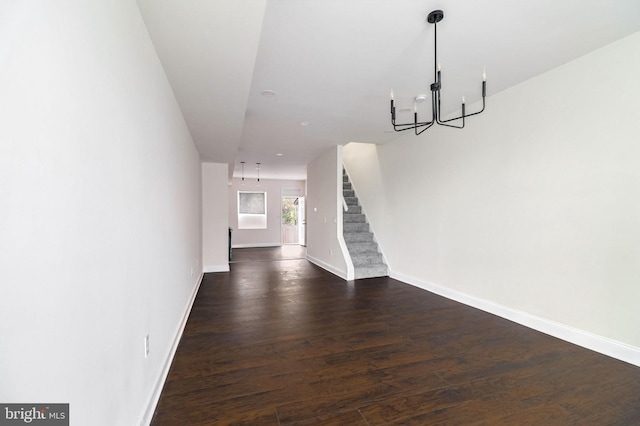 unfurnished living room with an inviting chandelier and dark hardwood / wood-style floors