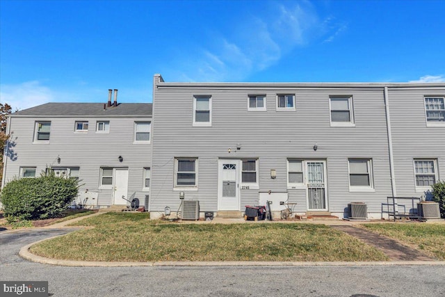 rear view of property featuring central AC and a lawn