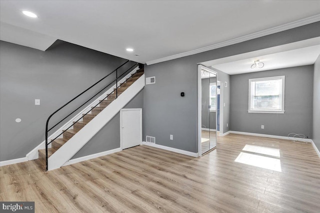 unfurnished living room with ornamental molding and light wood-type flooring