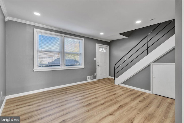 foyer entrance featuring crown molding and light hardwood / wood-style flooring