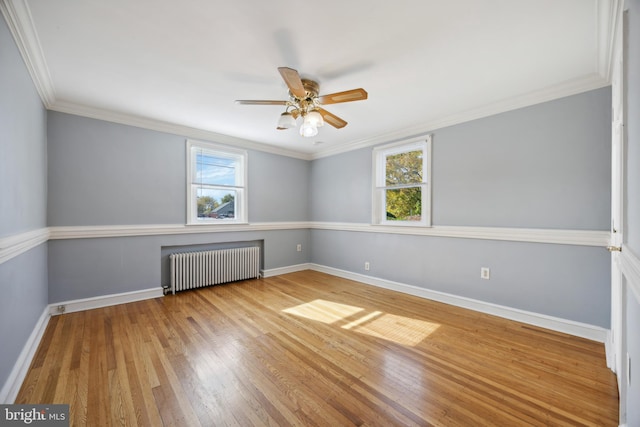 empty room featuring crown molding, hardwood / wood-style floors, radiator, and plenty of natural light