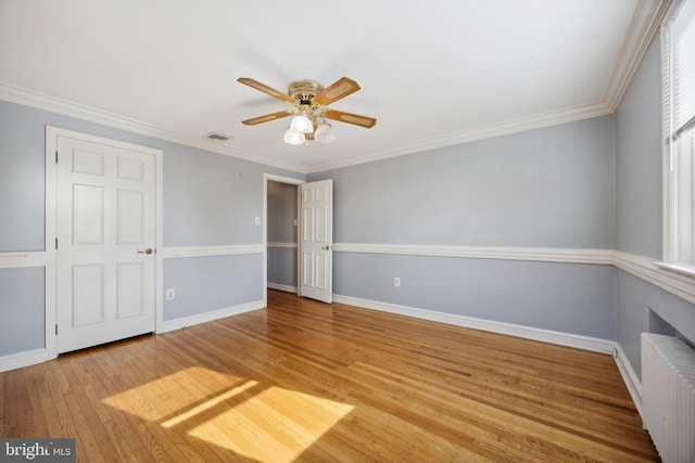 unfurnished bedroom with a closet, ornamental molding, hardwood / wood-style floors, radiator heating unit, and ceiling fan