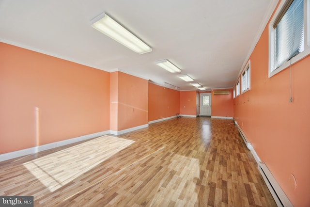 empty room with ornamental molding, a baseboard heating unit, and hardwood / wood-style floors