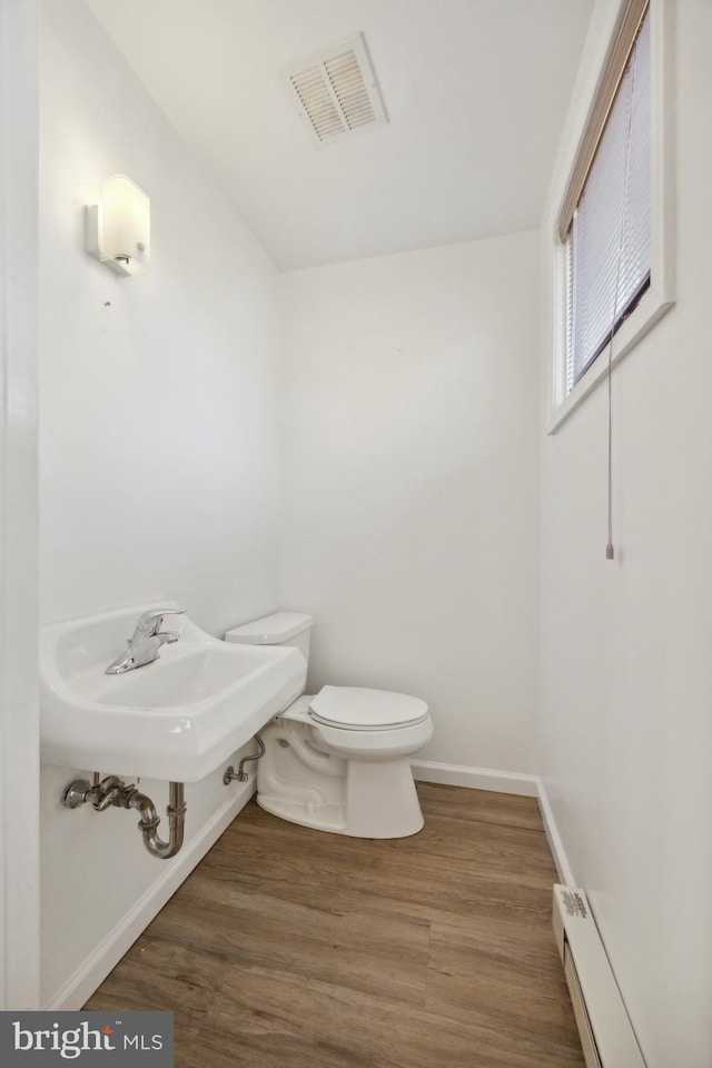 bathroom with toilet, hardwood / wood-style flooring, sink, and baseboard heating