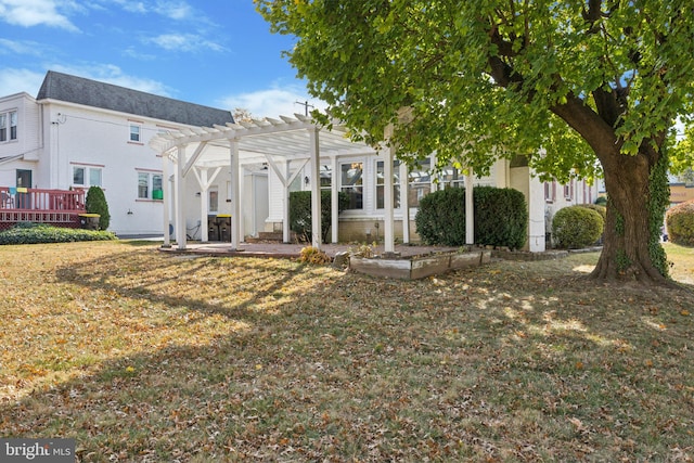 rear view of property featuring a pergola, a wooden deck, and a yard