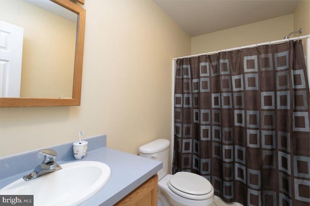 bathroom featuring toilet, vanity, and curtained shower