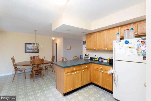 kitchen featuring pendant lighting, kitchen peninsula, a chandelier, and white refrigerator