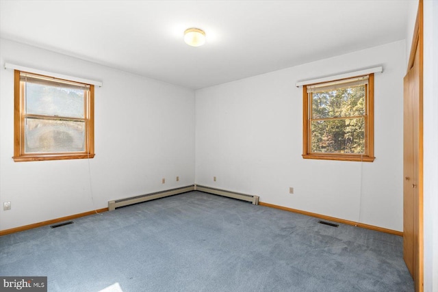 carpeted empty room featuring a baseboard heating unit