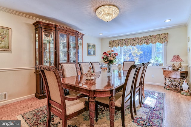 dining area featuring light hardwood / wood-style flooring, a chandelier, and crown molding