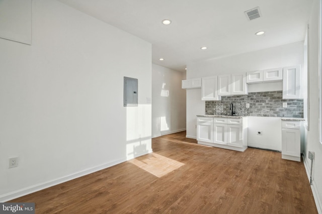 kitchen with white cabinetry, light wood-type flooring, electric panel, and sink