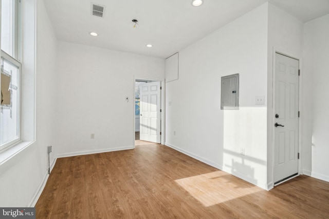 empty room with electric panel and hardwood / wood-style flooring