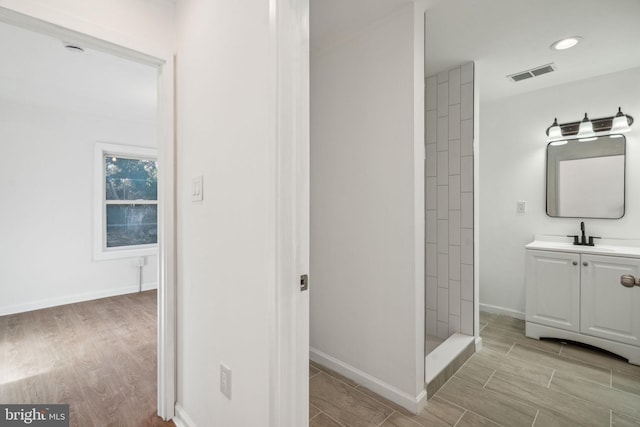 bathroom featuring walk in shower, vanity, and hardwood / wood-style floors