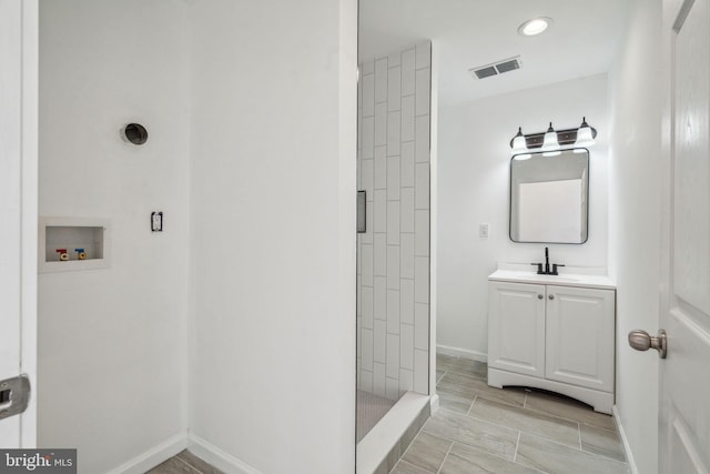 bathroom with vanity and tiled shower