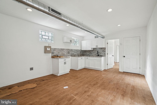 kitchen with white cabinets, sink, light hardwood / wood-style flooring, and decorative backsplash