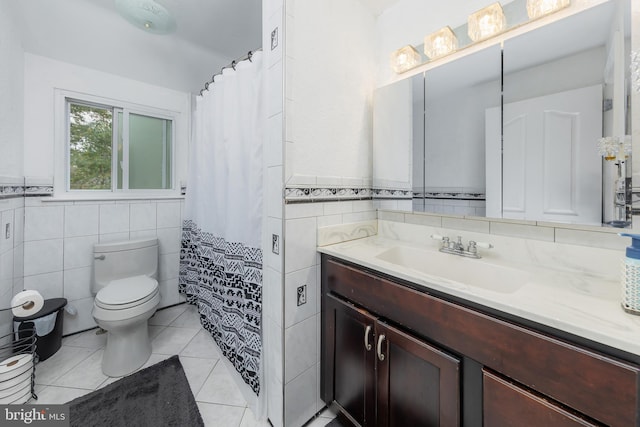 bathroom with tile walls, vanity, toilet, and tile patterned flooring