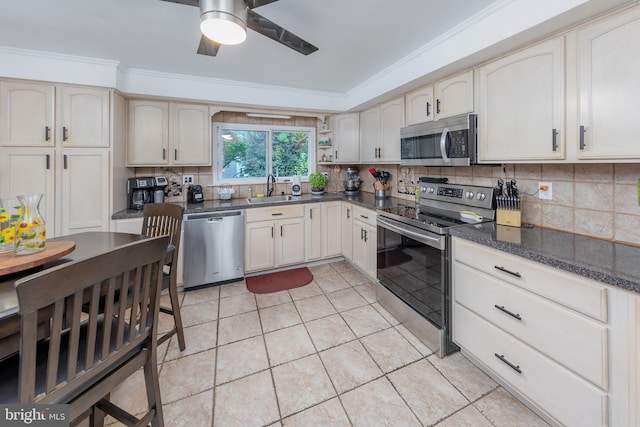 kitchen with appliances with stainless steel finishes, light tile patterned flooring, sink, dark stone countertops, and crown molding