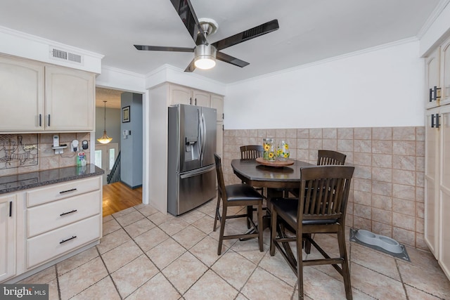 kitchen featuring ceiling fan, pendant lighting, dark stone countertops, crown molding, and stainless steel refrigerator with ice dispenser