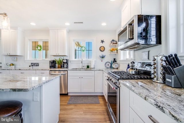 kitchen featuring a breakfast bar area, light hardwood / wood-style flooring, stainless steel appliances, sink, and white cabinetry