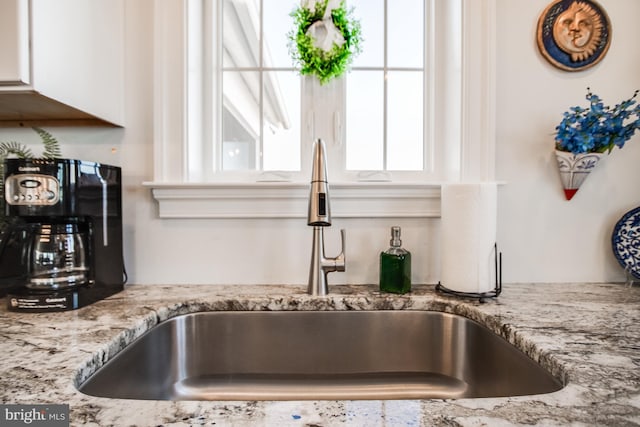 room details featuring white cabinetry, light stone countertops, and sink