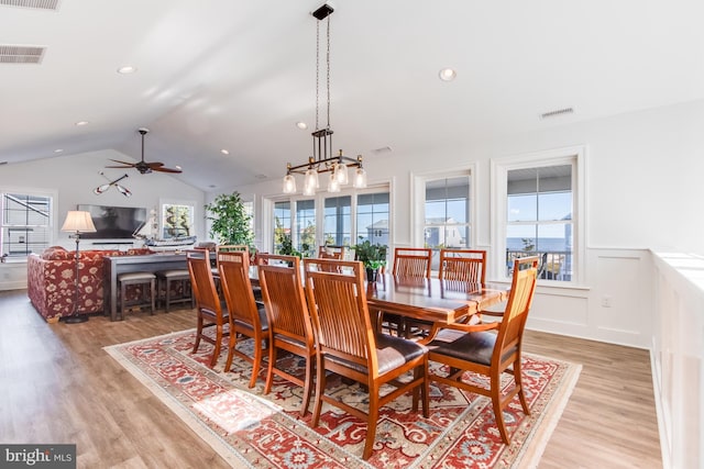 dining space with light hardwood / wood-style floors, ceiling fan, and vaulted ceiling