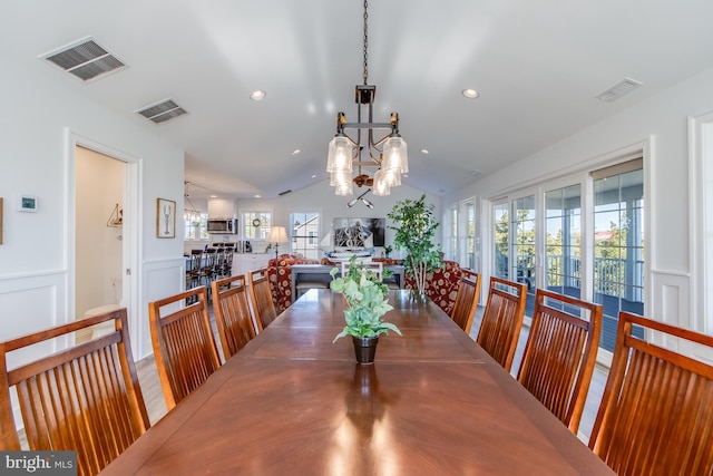 dining space featuring hardwood / wood-style flooring, a notable chandelier, and lofted ceiling