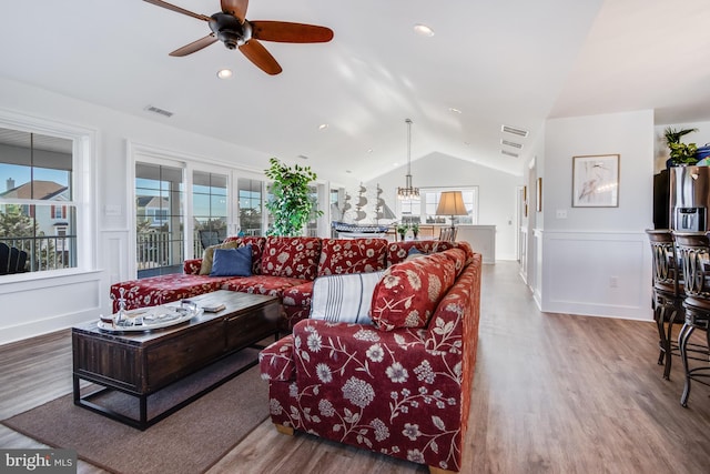 living room featuring hardwood / wood-style floors, ceiling fan with notable chandelier, and vaulted ceiling