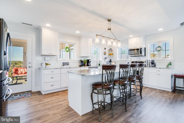 kitchen with a center island, appliances with stainless steel finishes, white cabinets, and plenty of natural light