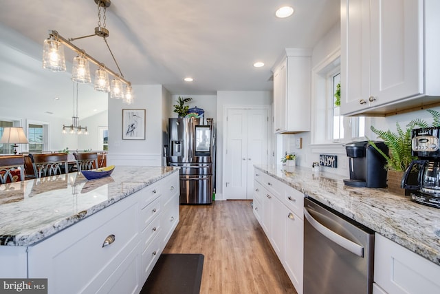 kitchen featuring stainless steel appliances, vaulted ceiling, pendant lighting, light wood-type flooring, and white cabinetry