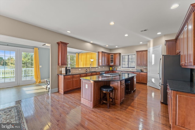 20069 Forest Farm Ln, Ashburn, VA 20147 - kitchen featuring a breakfast bar area, wood finished floors, a sink, decorative backsplash, and a kitchen island