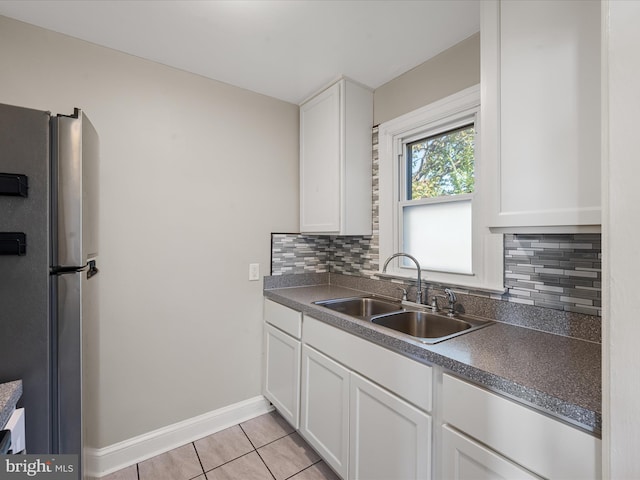 kitchen featuring sink, stainless steel fridge, white cabinets, and tasteful backsplash