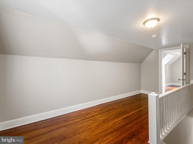 additional living space with vaulted ceiling and dark hardwood / wood-style flooring