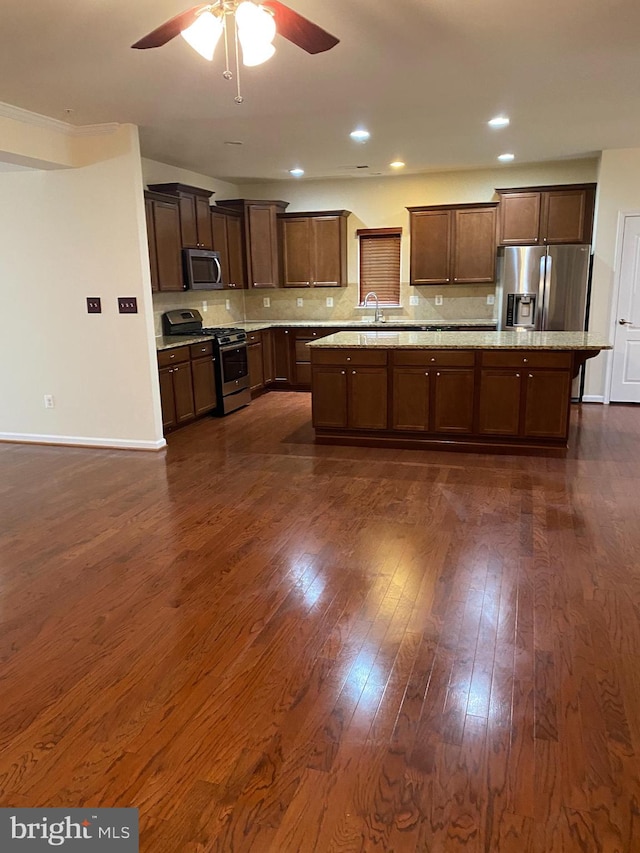 kitchen featuring appliances with stainless steel finishes, dark hardwood / wood-style flooring, sink, ceiling fan, and a center island