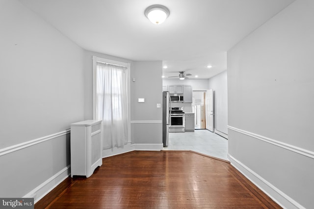 unfurnished living room with ceiling fan, hardwood / wood-style flooring, and baseboard heating