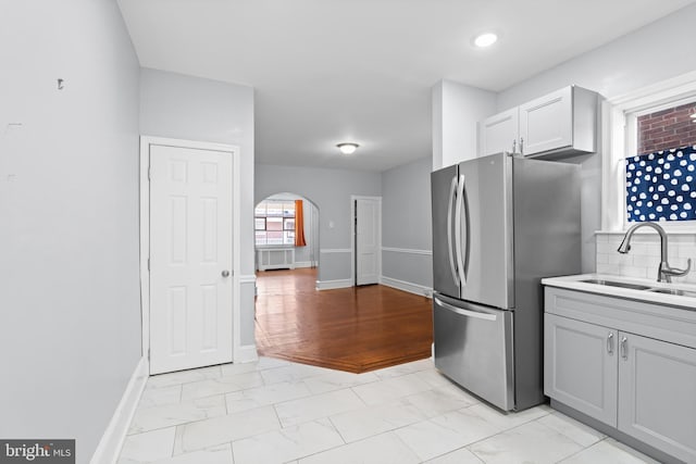 kitchen featuring gray cabinetry, sink, decorative backsplash, light hardwood / wood-style floors, and stainless steel refrigerator