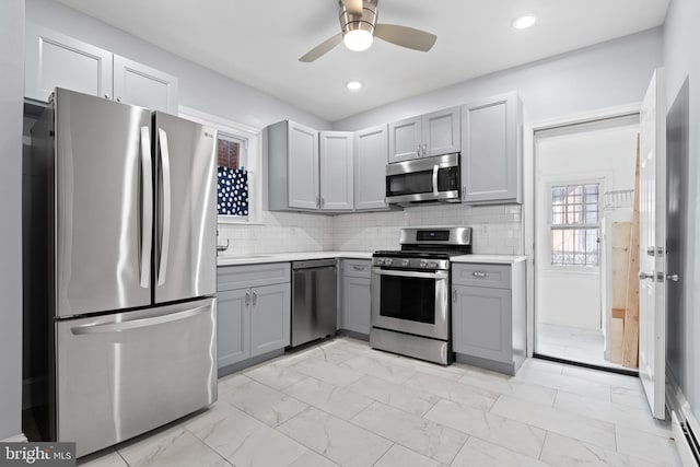 kitchen featuring appliances with stainless steel finishes, tasteful backsplash, gray cabinets, and ceiling fan