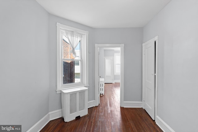 corridor with radiator heating unit and dark hardwood / wood-style flooring