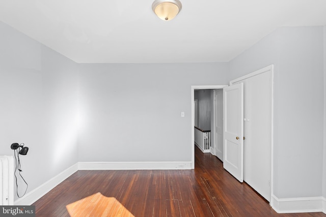 unfurnished room featuring dark hardwood / wood-style floors and radiator heating unit