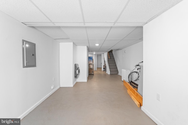 basement with electric panel, a paneled ceiling, and heating unit