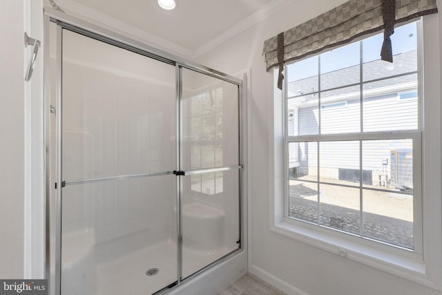 bathroom featuring a shower with door and crown molding