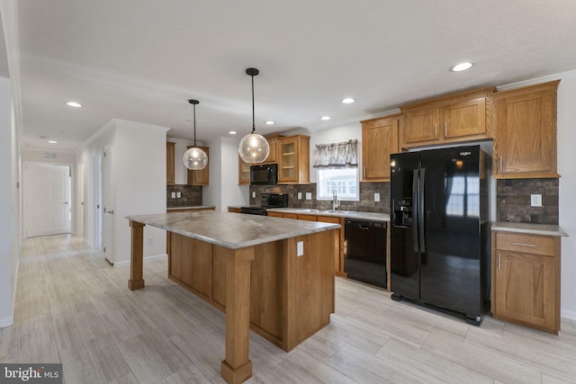 kitchen with crown molding, decorative light fixtures, a breakfast bar area, a kitchen island, and black appliances