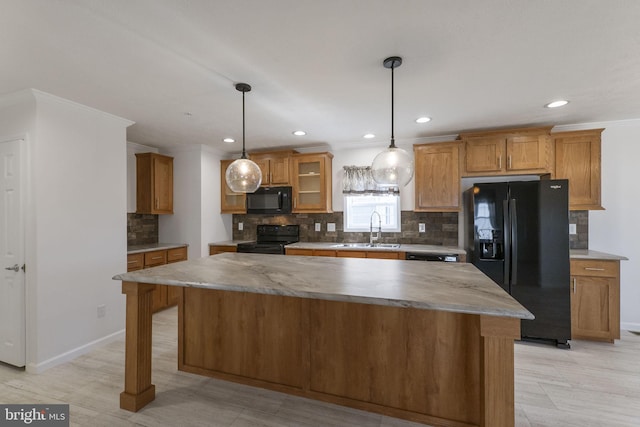 kitchen with hanging light fixtures, crown molding, a center island, and black appliances