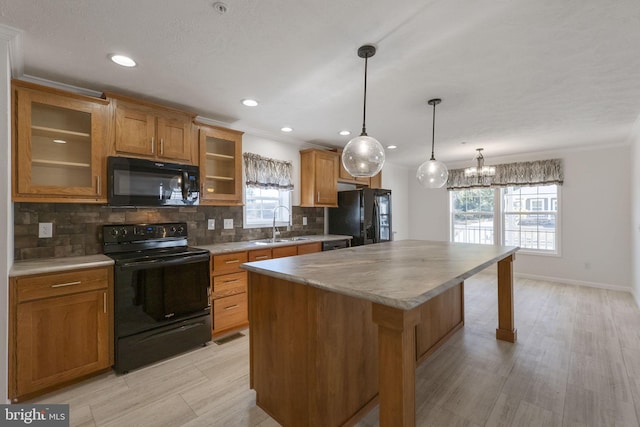 kitchen featuring decorative backsplash, light wood-type flooring, black appliances, decorative light fixtures, and a center island