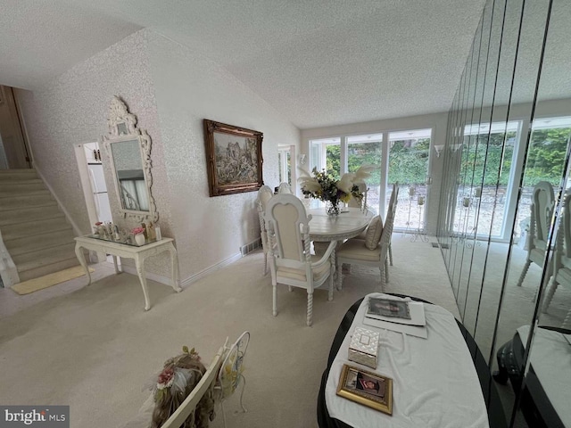 carpeted dining area with lofted ceiling and a textured ceiling