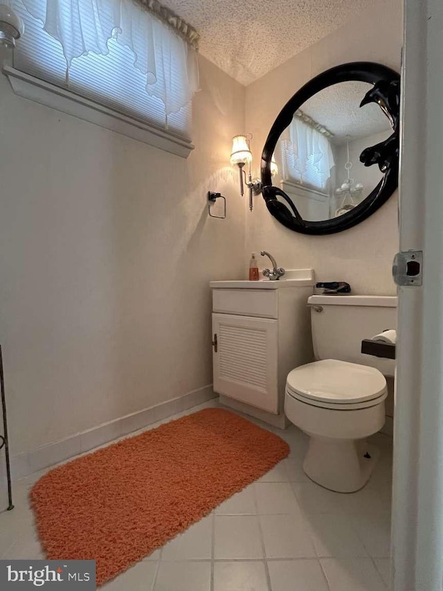 bathroom with vanity, toilet, a textured ceiling, and tile patterned flooring