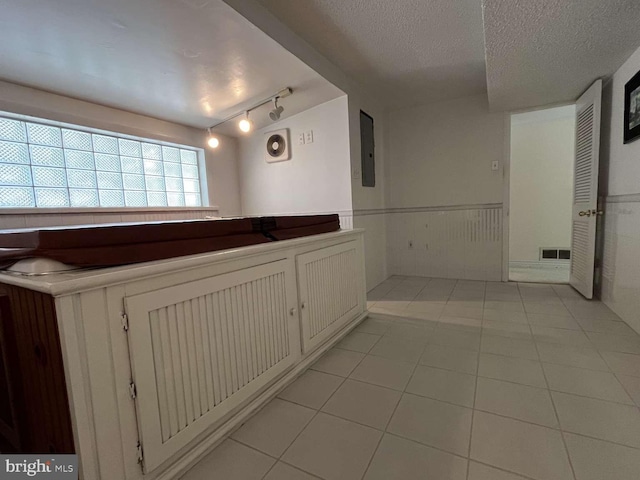 bathroom featuring tile patterned floors, electric panel, a textured ceiling, and rail lighting