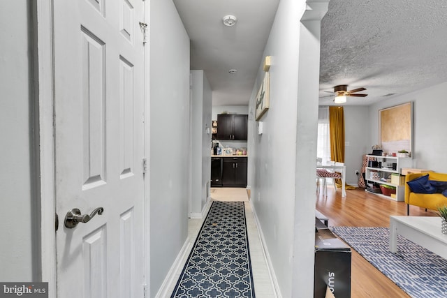 hallway featuring light wood-type flooring and a textured ceiling