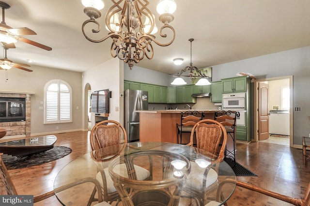 dining space featuring ceiling fan with notable chandelier and dark hardwood / wood-style flooring