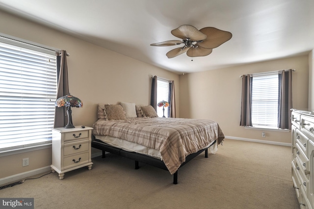 bedroom featuring multiple windows, light colored carpet, and ceiling fan